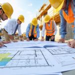 Construction professionals conducting a review of building plans and licenses at a Virginia construction site, with hard hats, certification documents, and tools symbolizing regulatory compliance and project management.