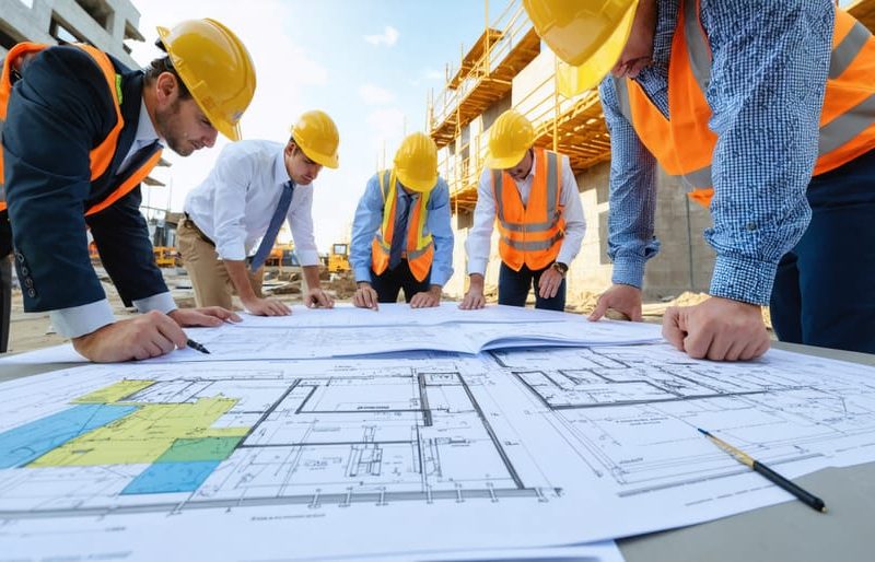 Construction professionals conducting a review of building plans and licenses at a Virginia construction site, with hard hats, certification documents, and tools symbolizing regulatory compliance and project management.