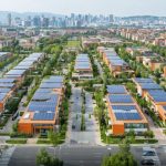 A diverse urban neighborhood showcasing solar panels on rooftops and green spaces, symbolizing the integration of renewable energy solutions and sustainable urban planning.