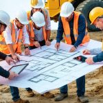 A diverse group of construction professionals, including engineers and architects, collaborating over architectural plans at an active job site.