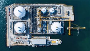 Aerial view of an advanced LNG export terminal under construction in the U.S., featuring large storage tanks, modular liquefaction units, and marine loading systems along a coastal location.