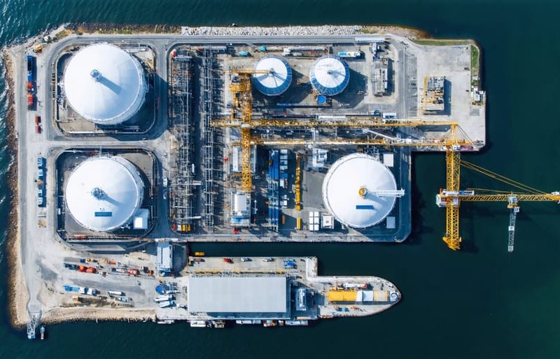 Aerial view of an advanced LNG export terminal under construction in the U.S., featuring large storage tanks, modular liquefaction units, and marine loading systems along a coastal location.